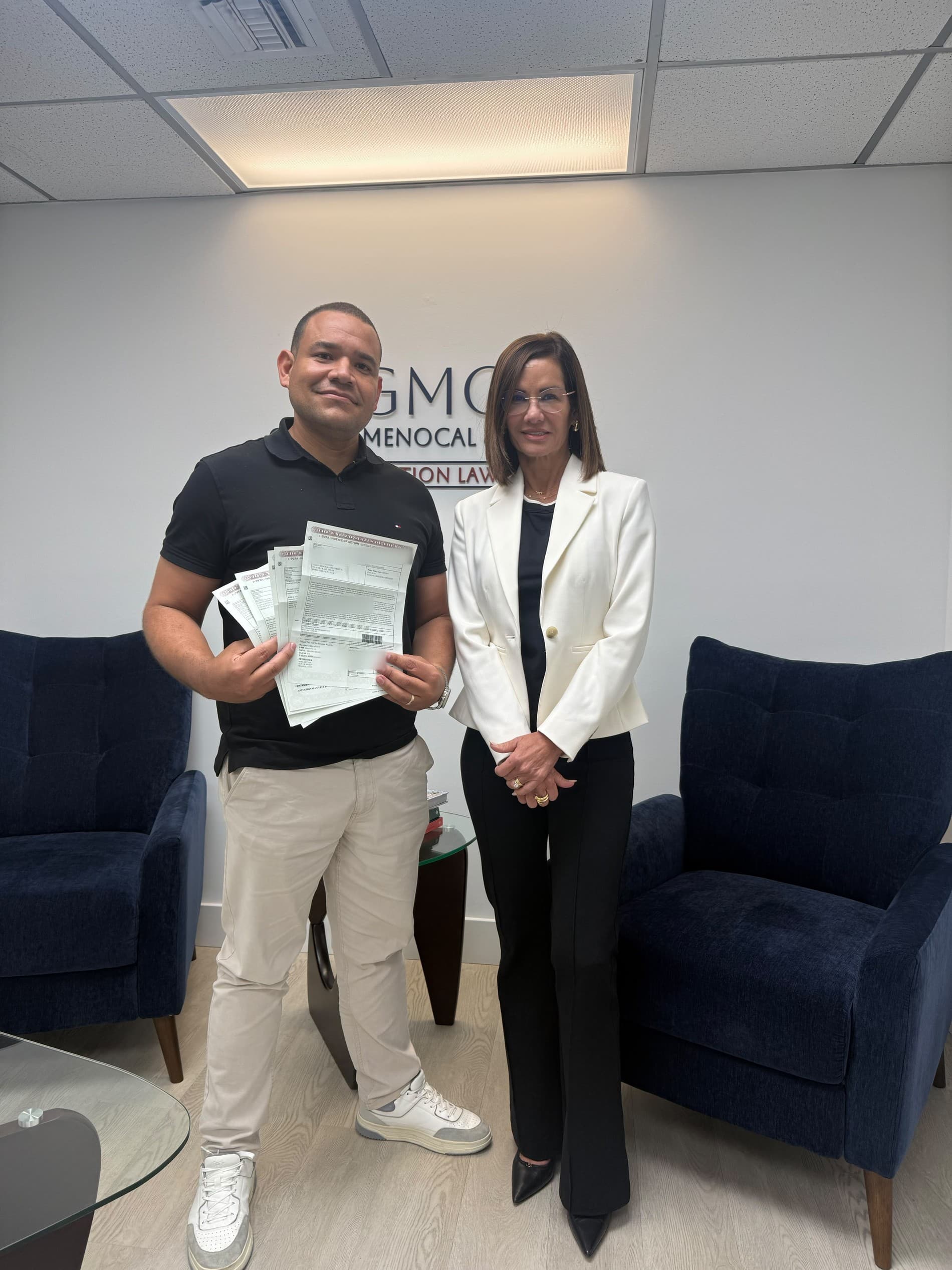 Cliente de GMC con documentos junto a una representante de la firma